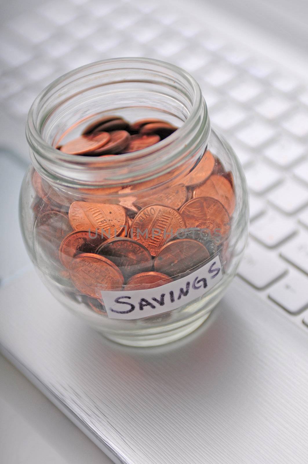 a concept of working a lot to save a little bit of money which is signified by a computer keyboard and pennies in a jar