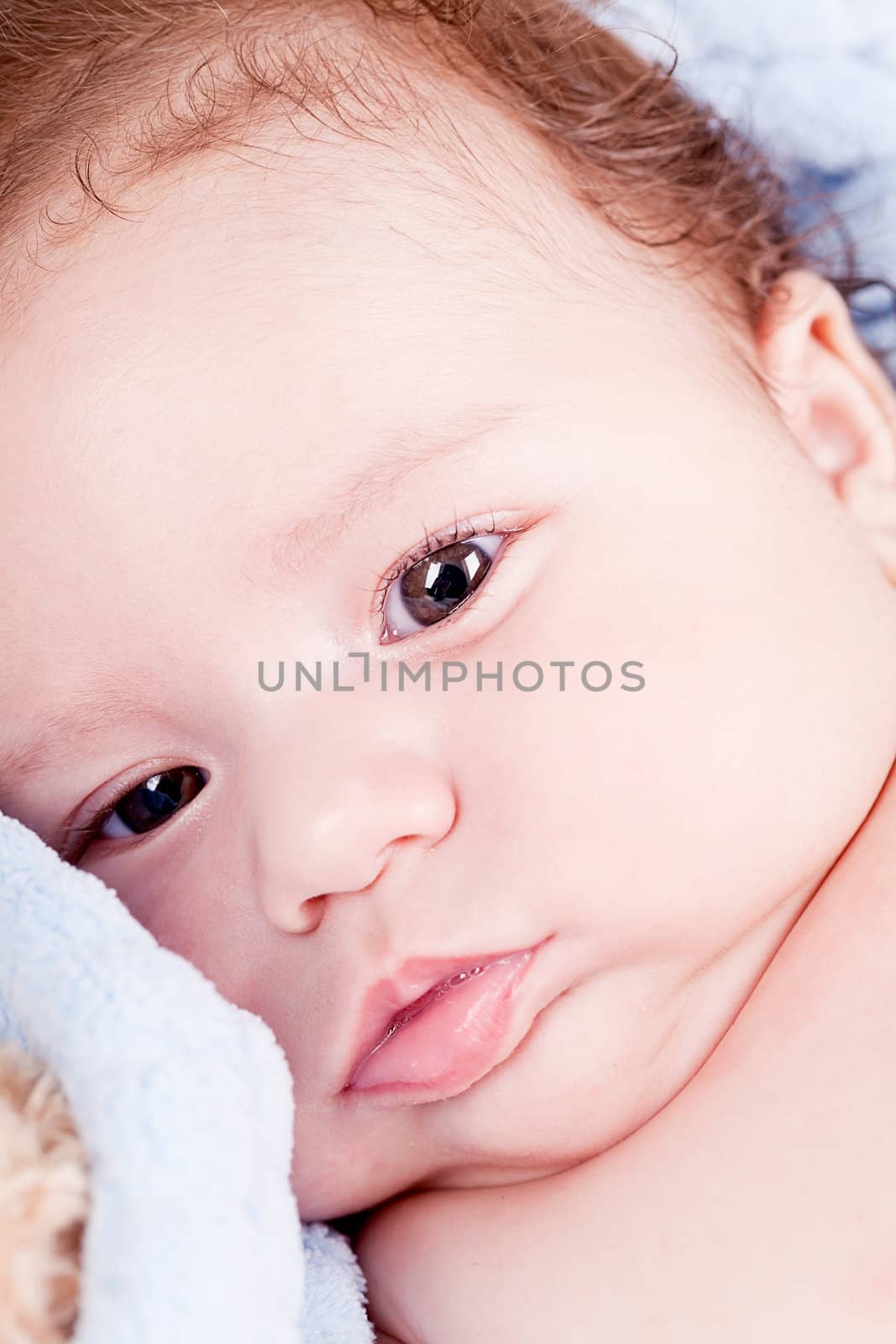cute little baby infant toddler lying on white blanket smiling portrait