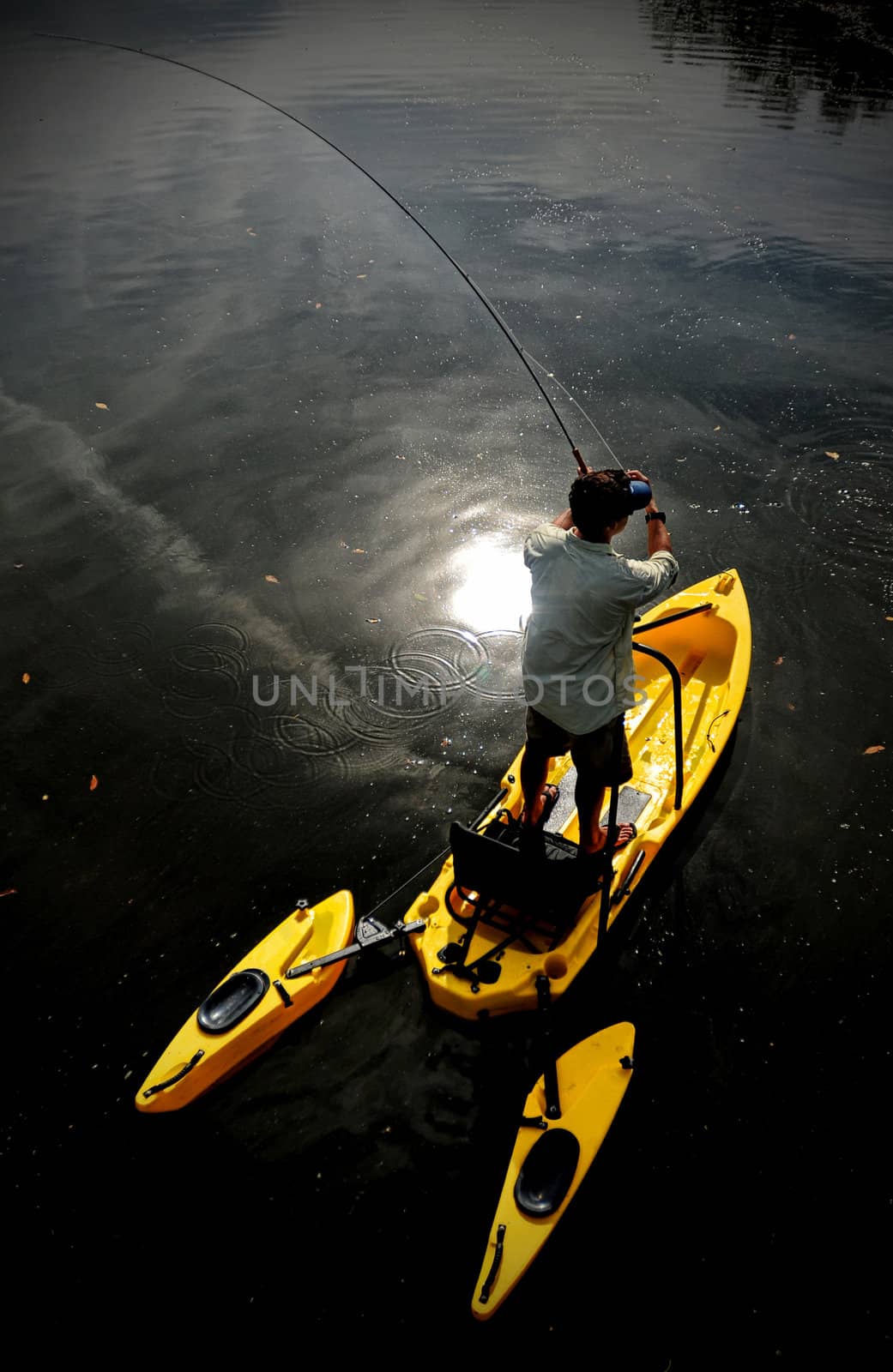 Man with brown hair fly fishing in a lake in a kayak