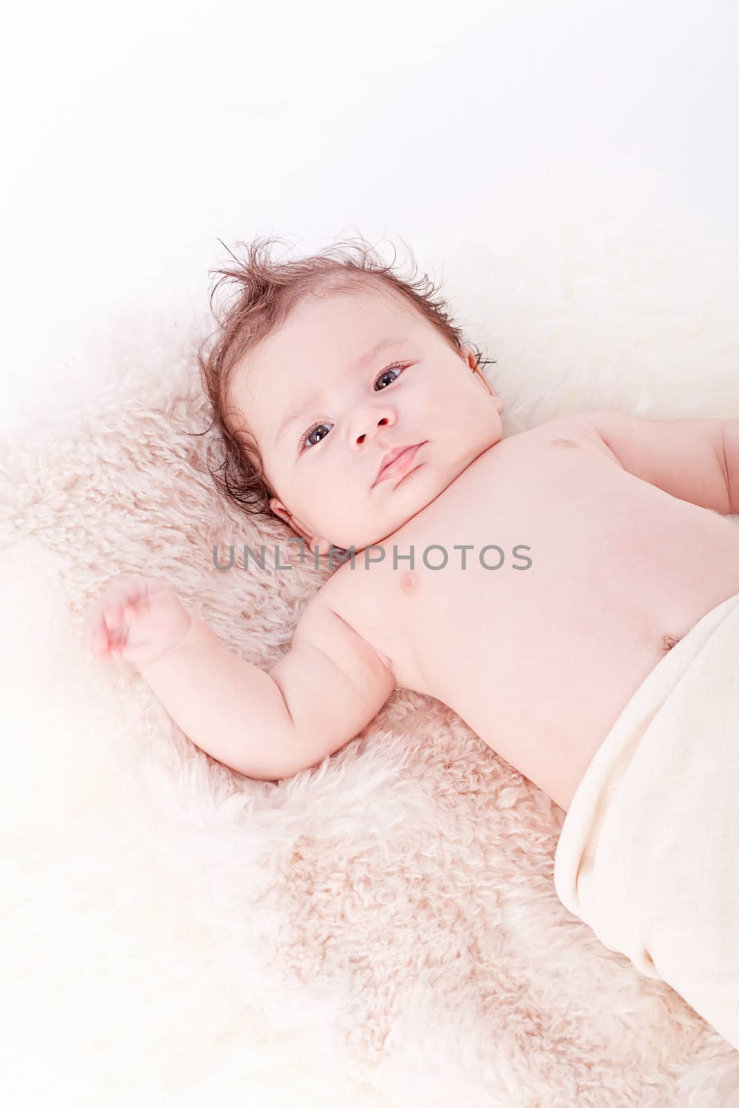 cute little baby infant toddler lying on white blanket smiling portrait