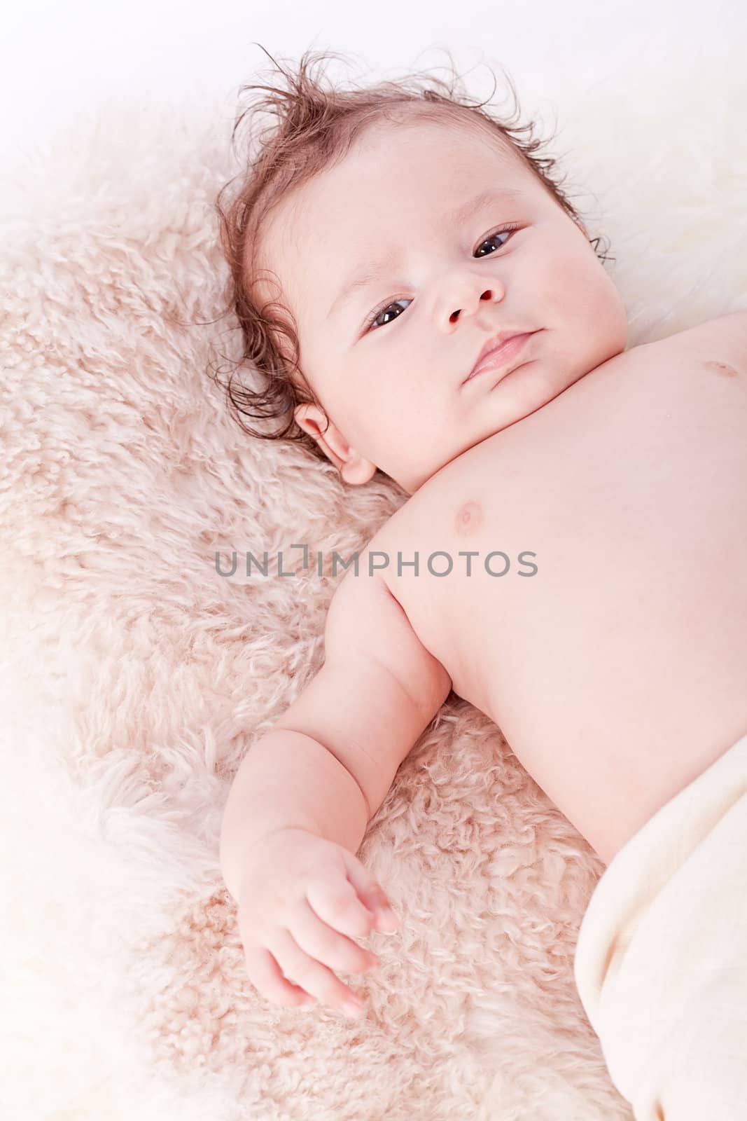 cute little baby infant toddler lying on white blanket smiling portrait