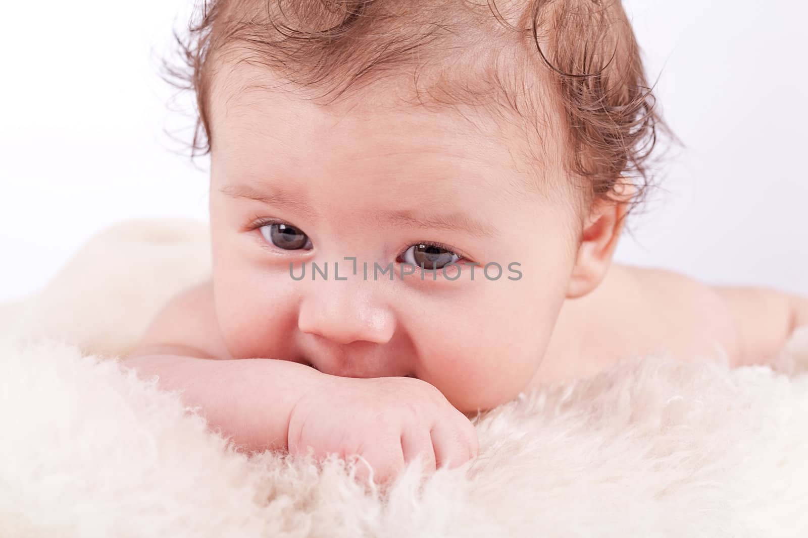 cute little baby infant toddler lying on white blanket smiling portrait
