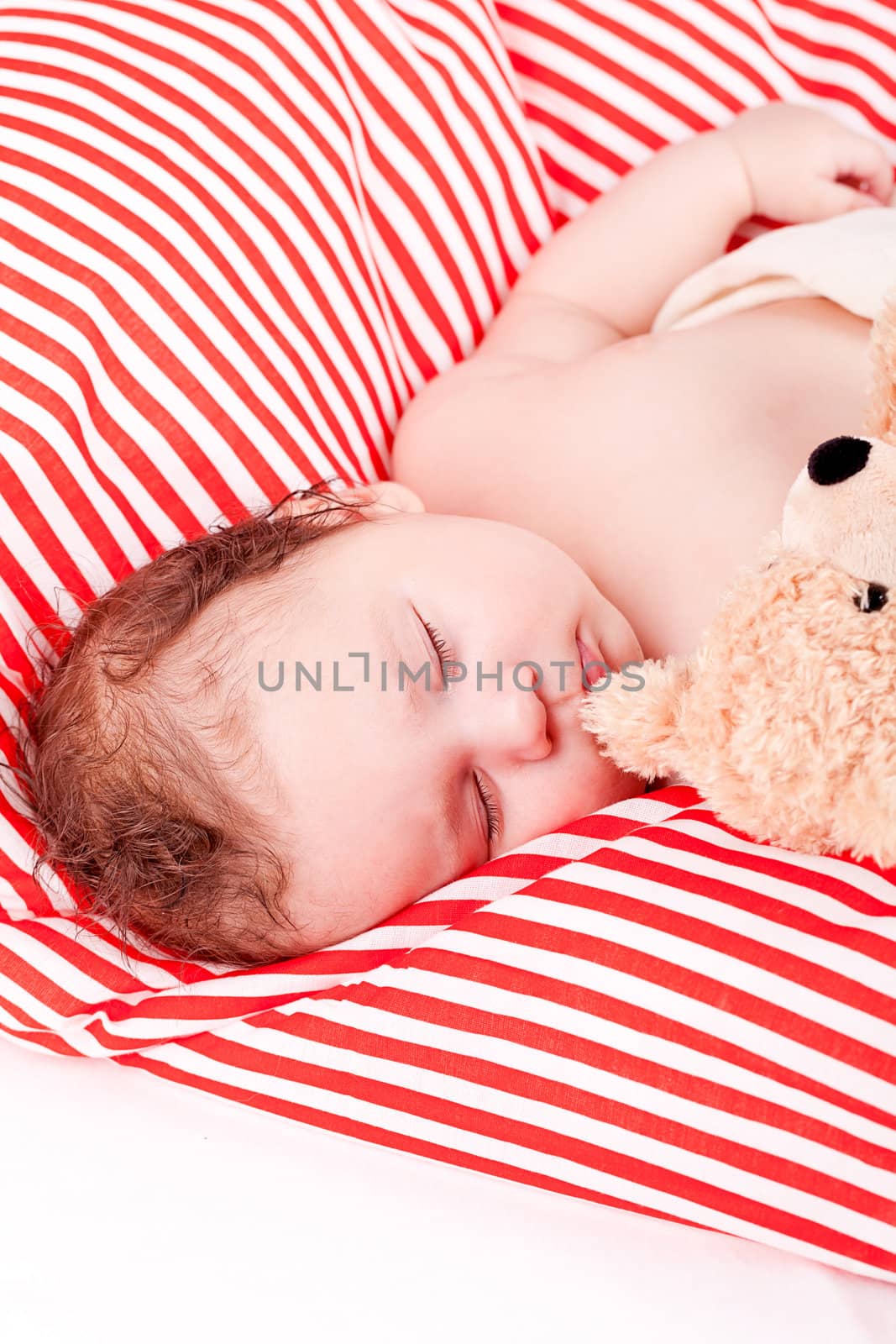 sleeping cute little baby on red and white stripes pillow with teddy bear
