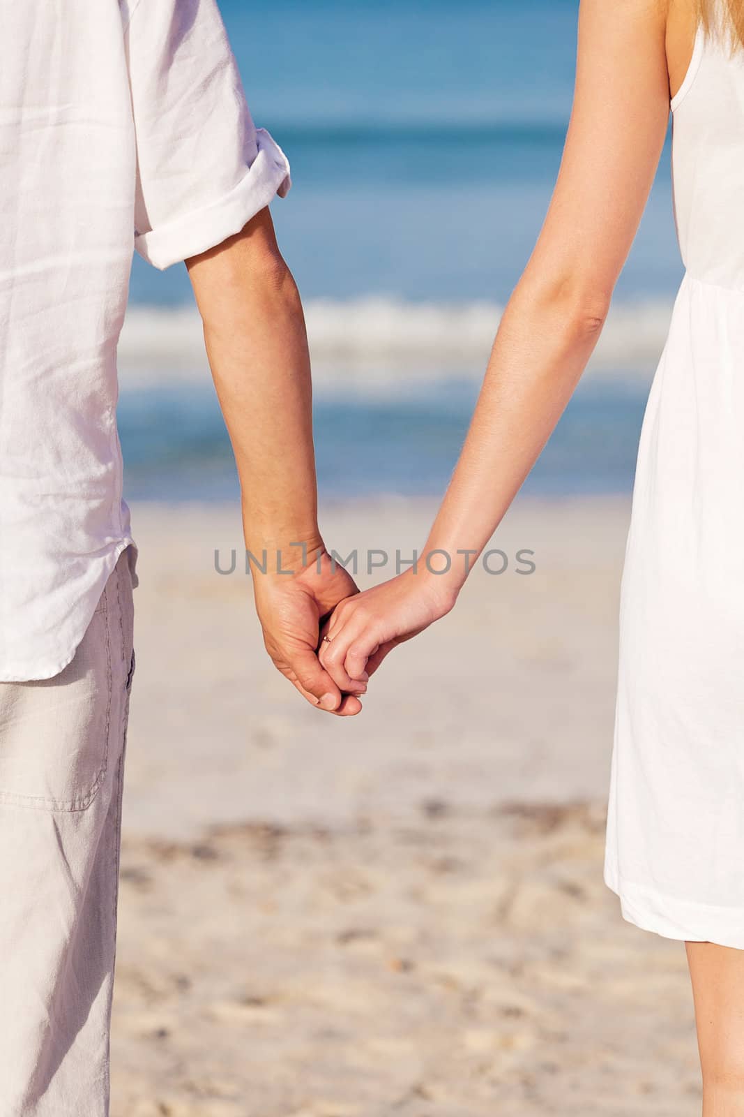 couple in love hand in hand on beach in summer holiday