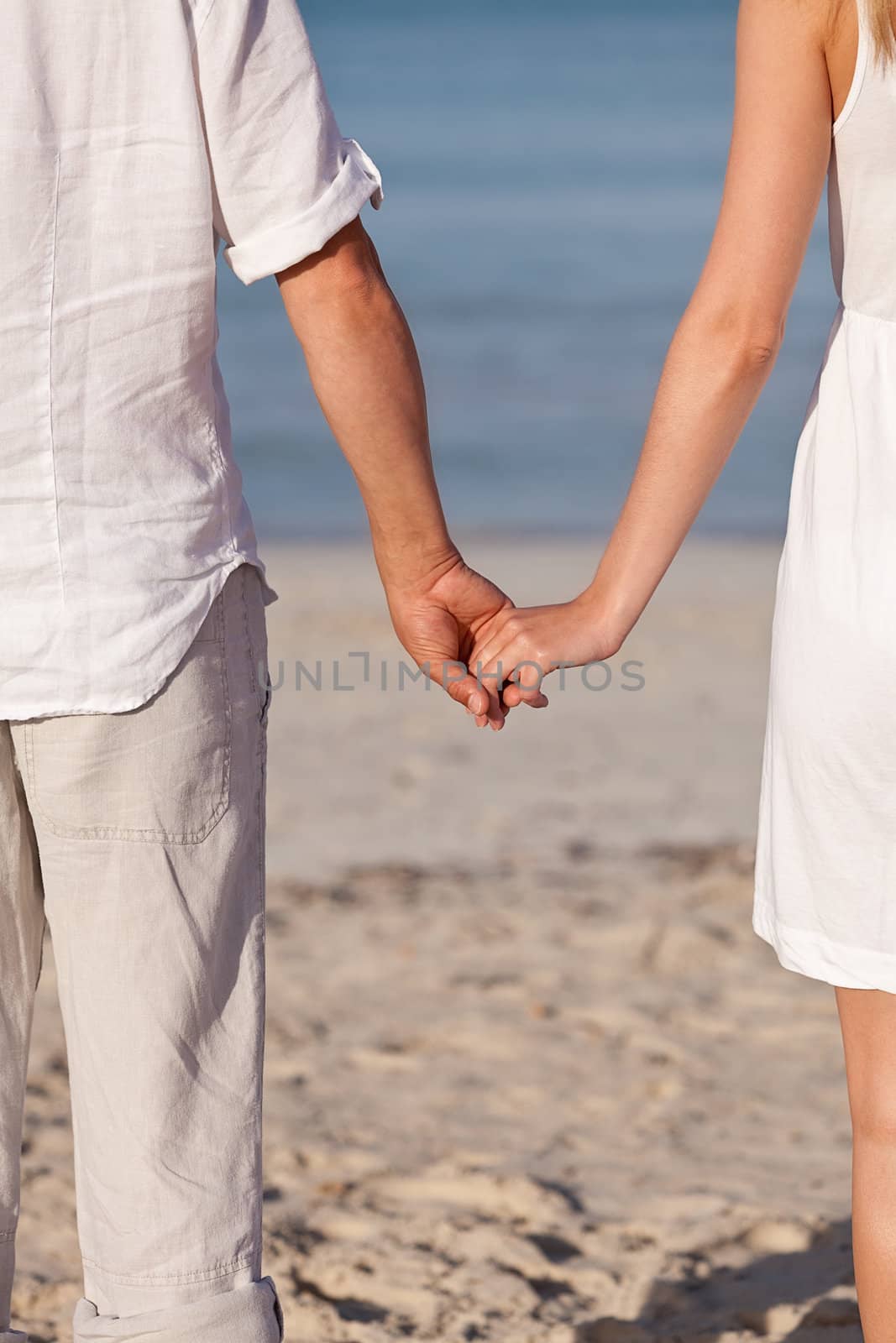 couple in love hand in hand on beach in summer holiday