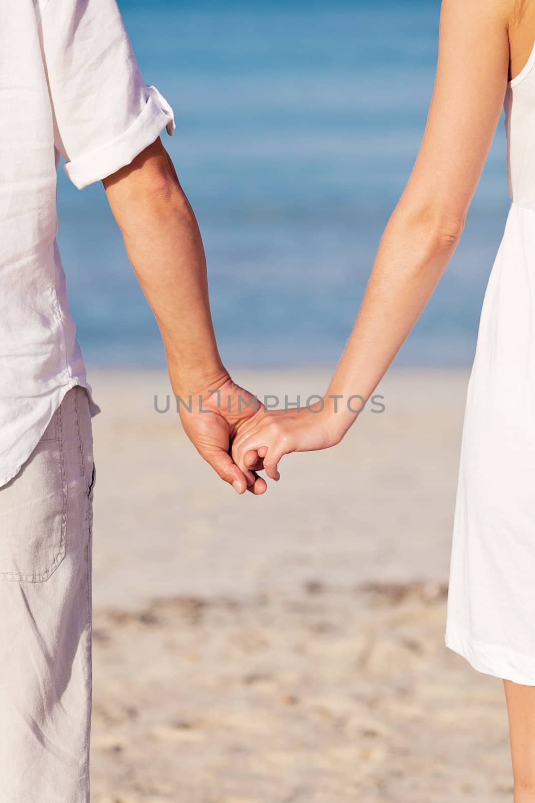 couple in love hand in hand on beach in summer holiday