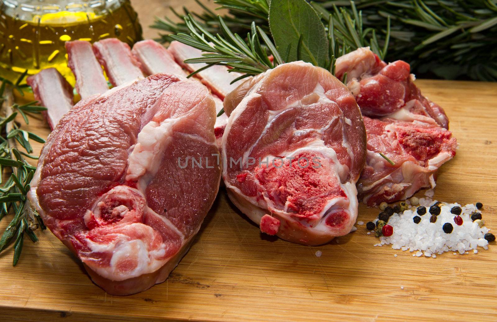 a group of rib lamb with oil and rosemary on wood table