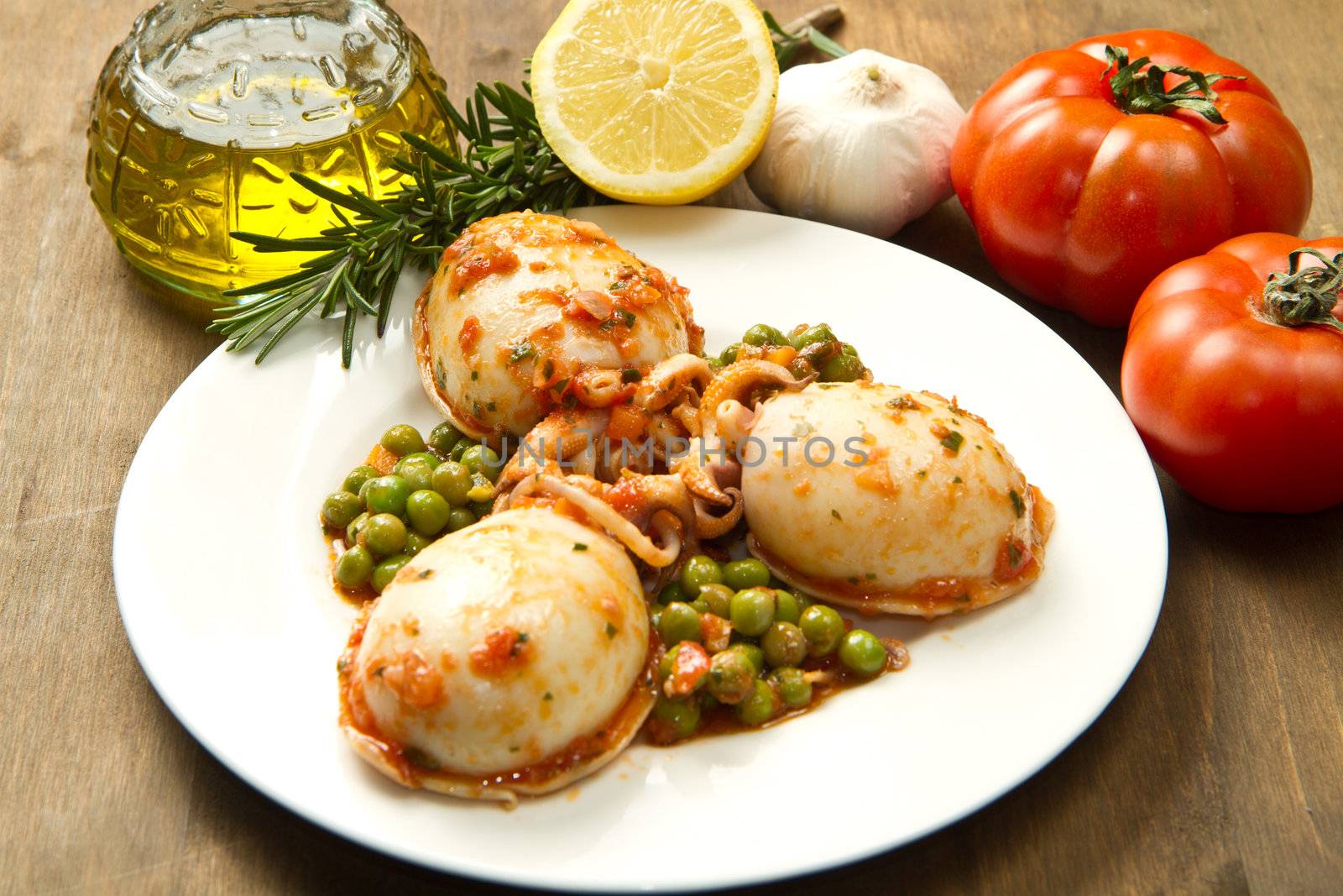 a white bowl with cuttlefish with peas and fresh tomatoes, lemon and oil