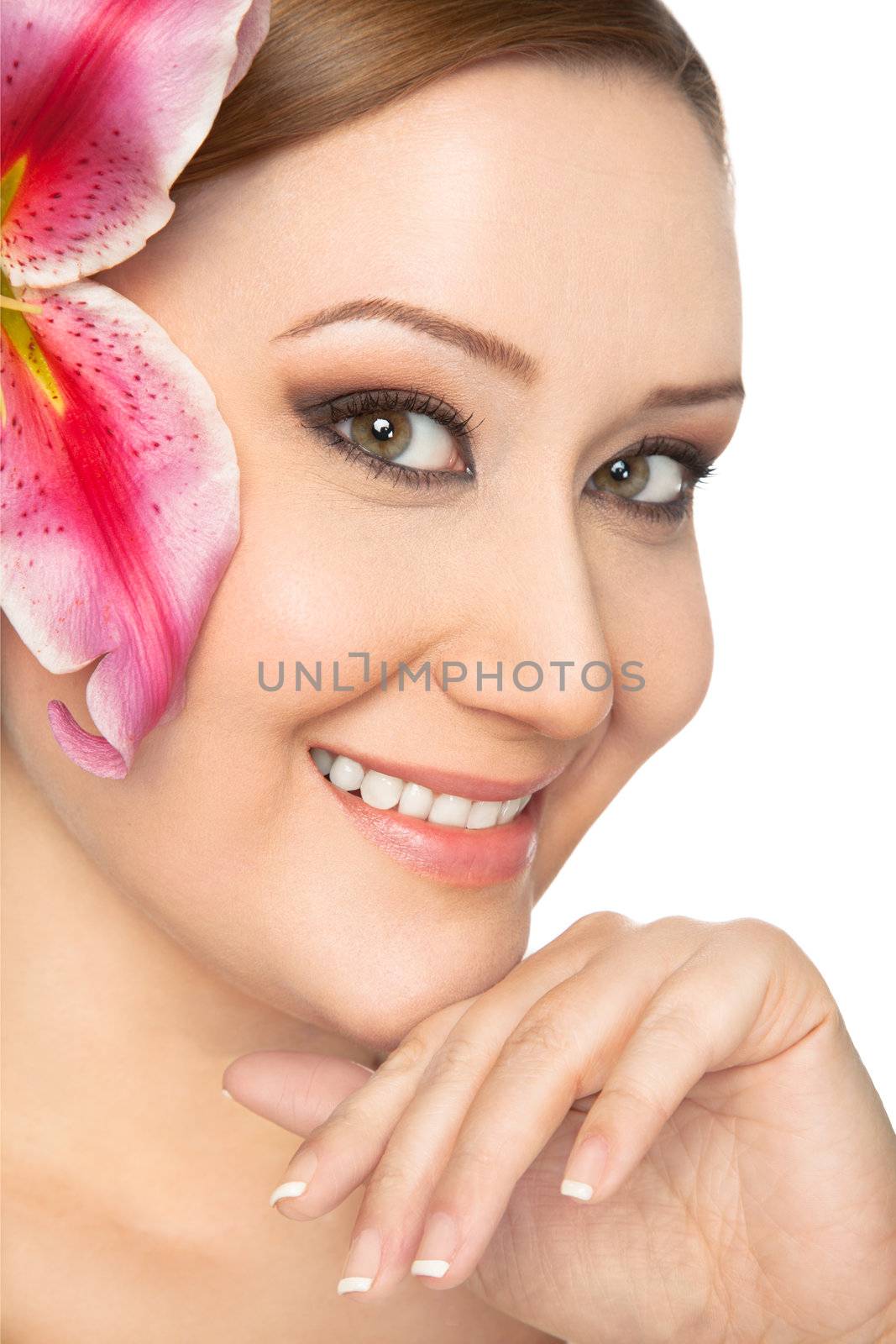 Portrait of smiling young woman with pink lily in her hair and hand under chin