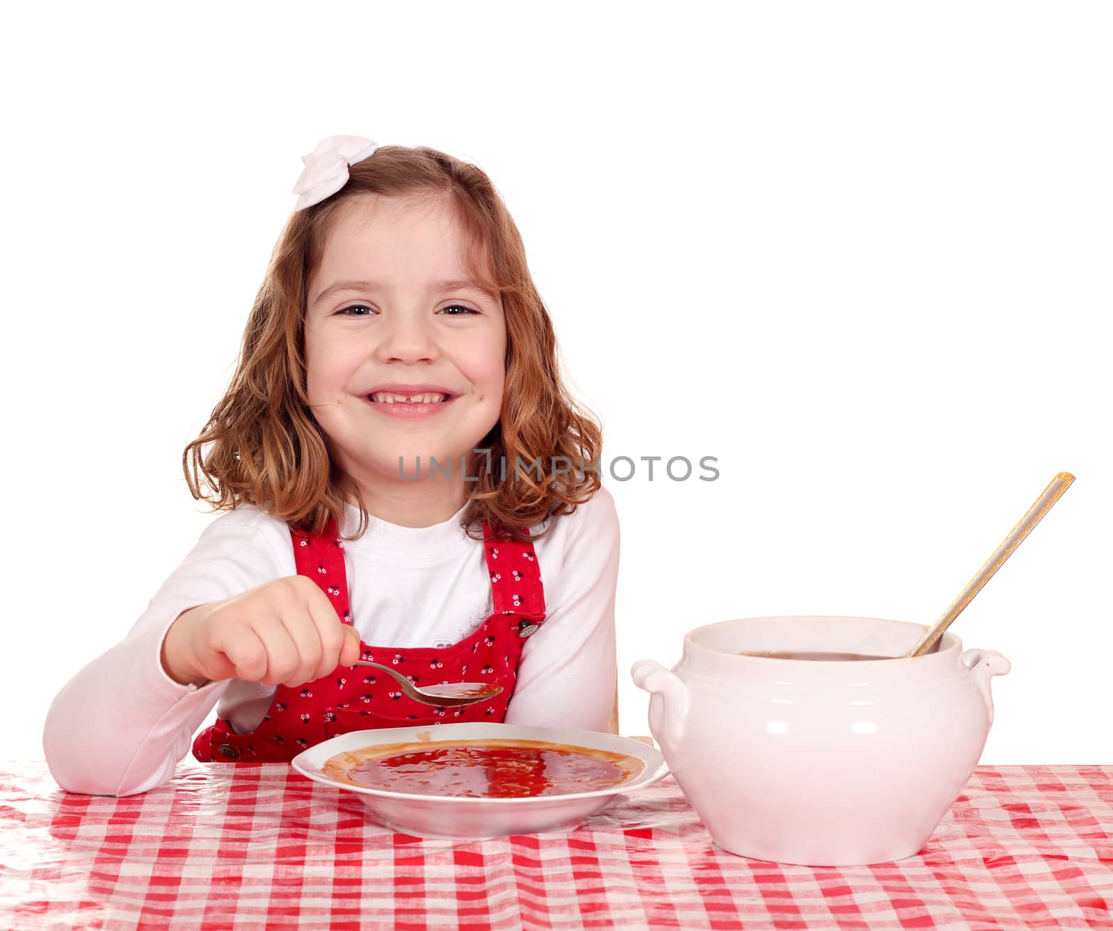 happy little girl eating red tomato soup