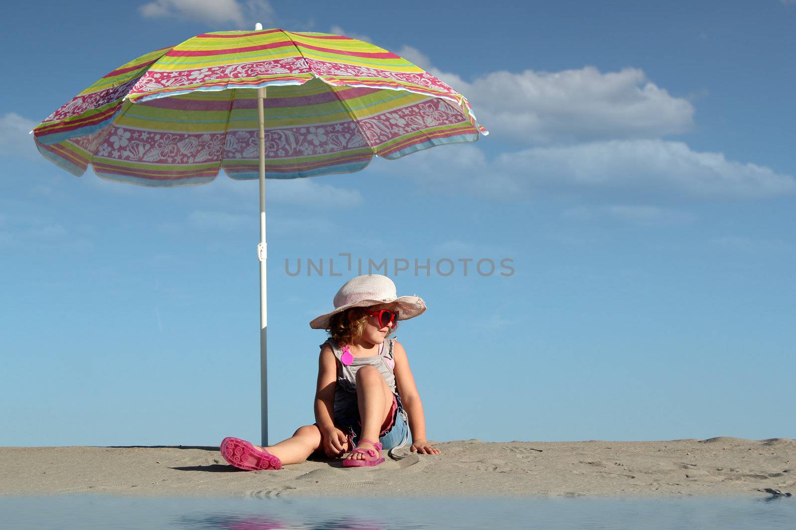 little girl with sunglasses sitting under sunshade