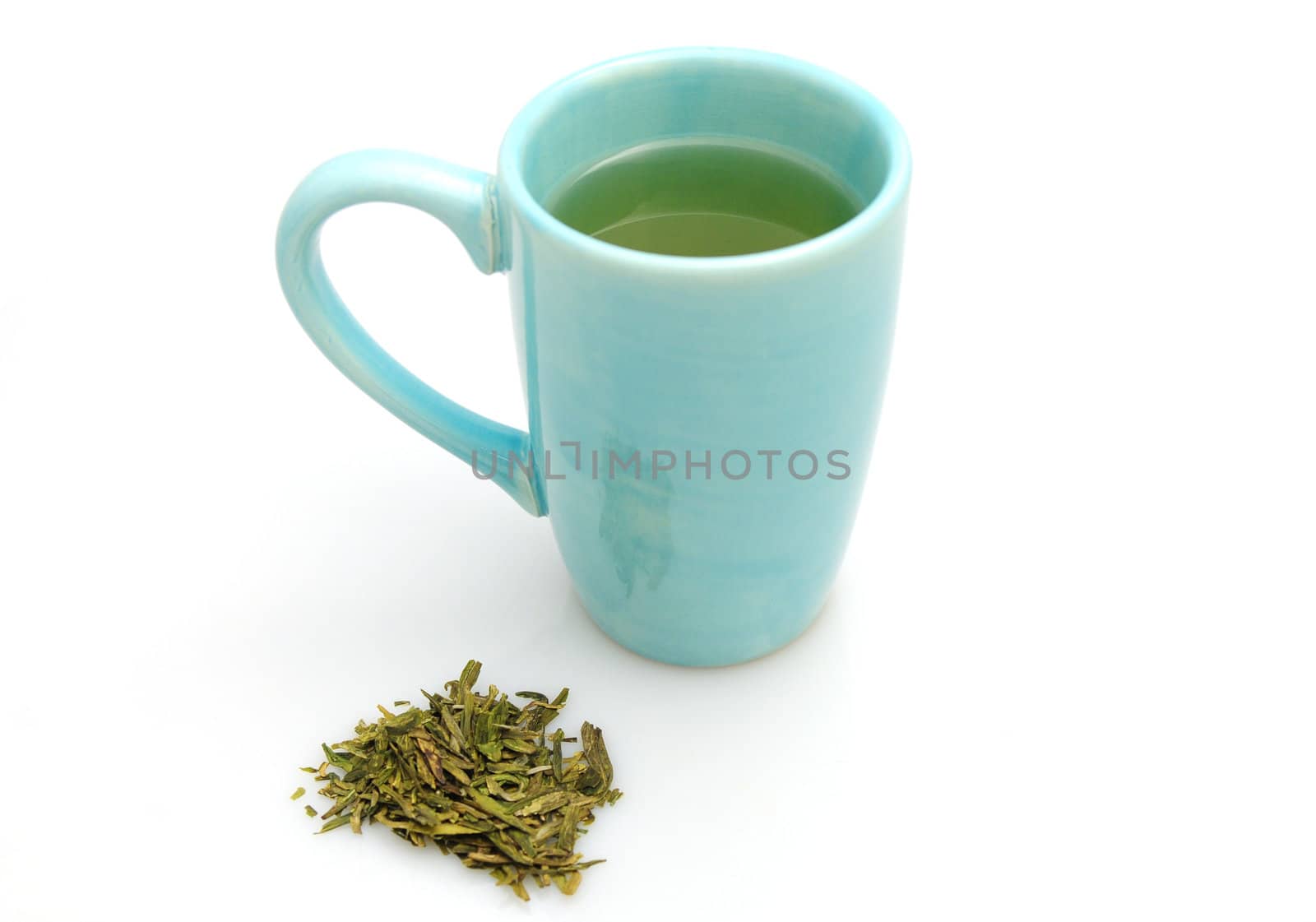 Blue mug of green tea with loose leaf green tea leaves isolated on white