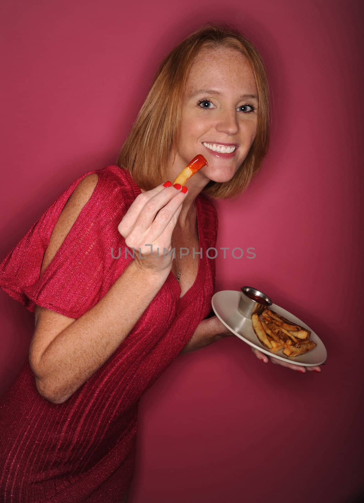 Attrractive woman eating junk food on a pink background