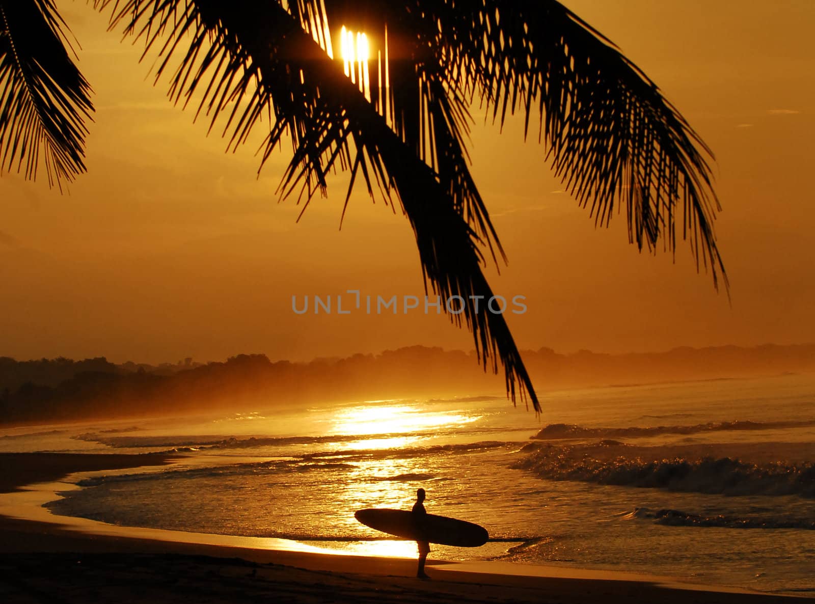 Costa Rica sunset with surfer admiring the waves