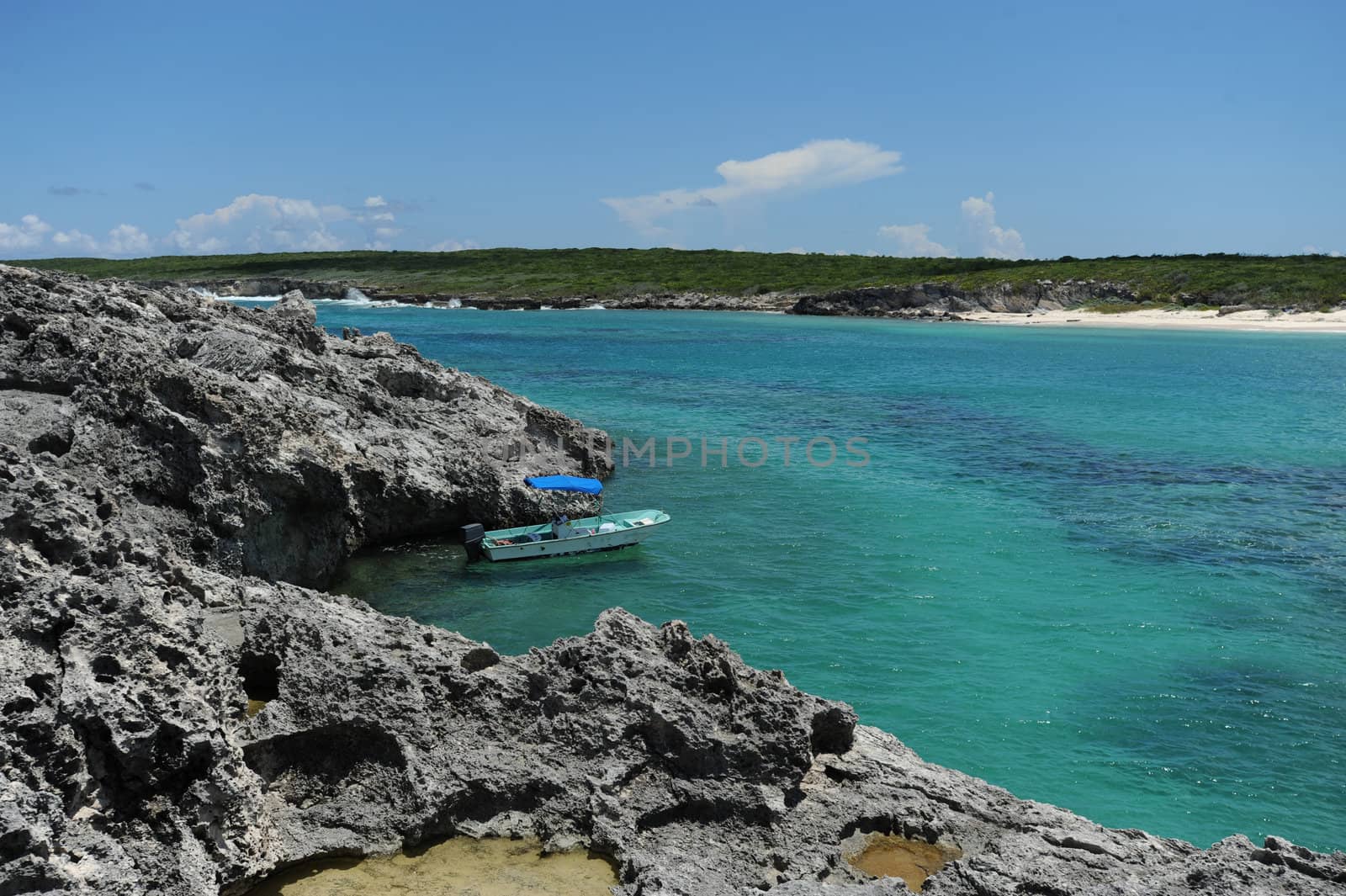 Small boat in tropical setting anchored near rocky island in the Caribbean
