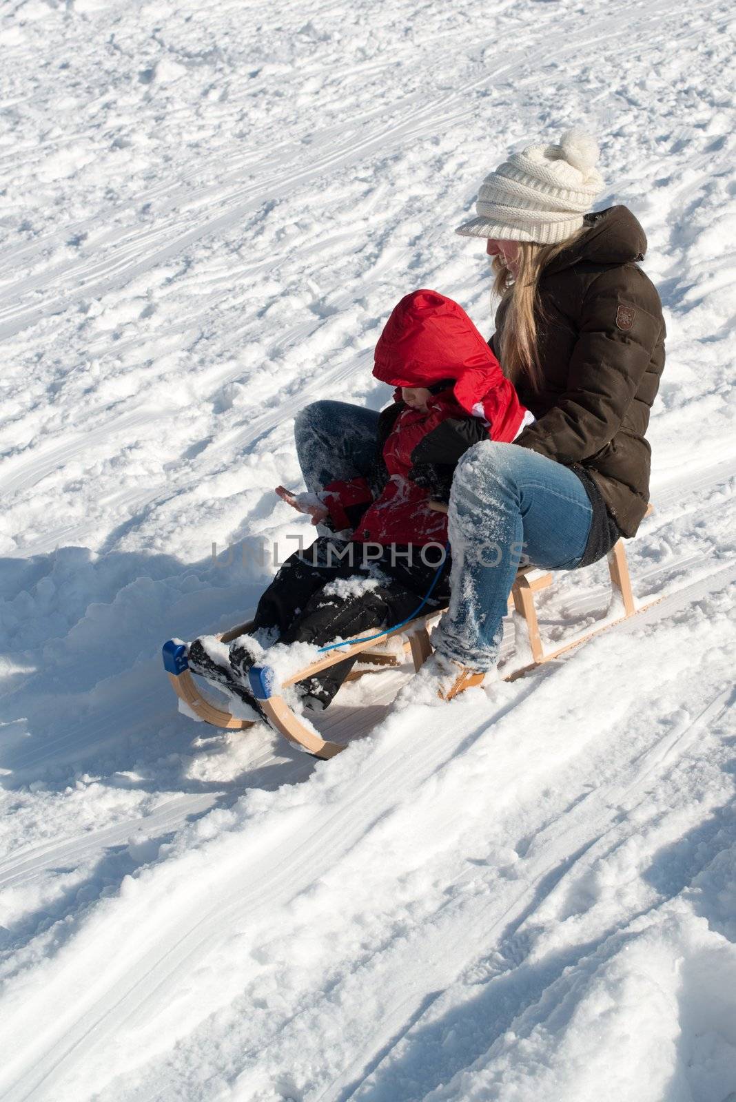 Stuttgart, Germany – February 9, 2013: Mother and child having fun with their sledge, bright and white winter scene on February 9, 2013 on the hills of Feuerbacher Heide in Stuttgart, Germany.