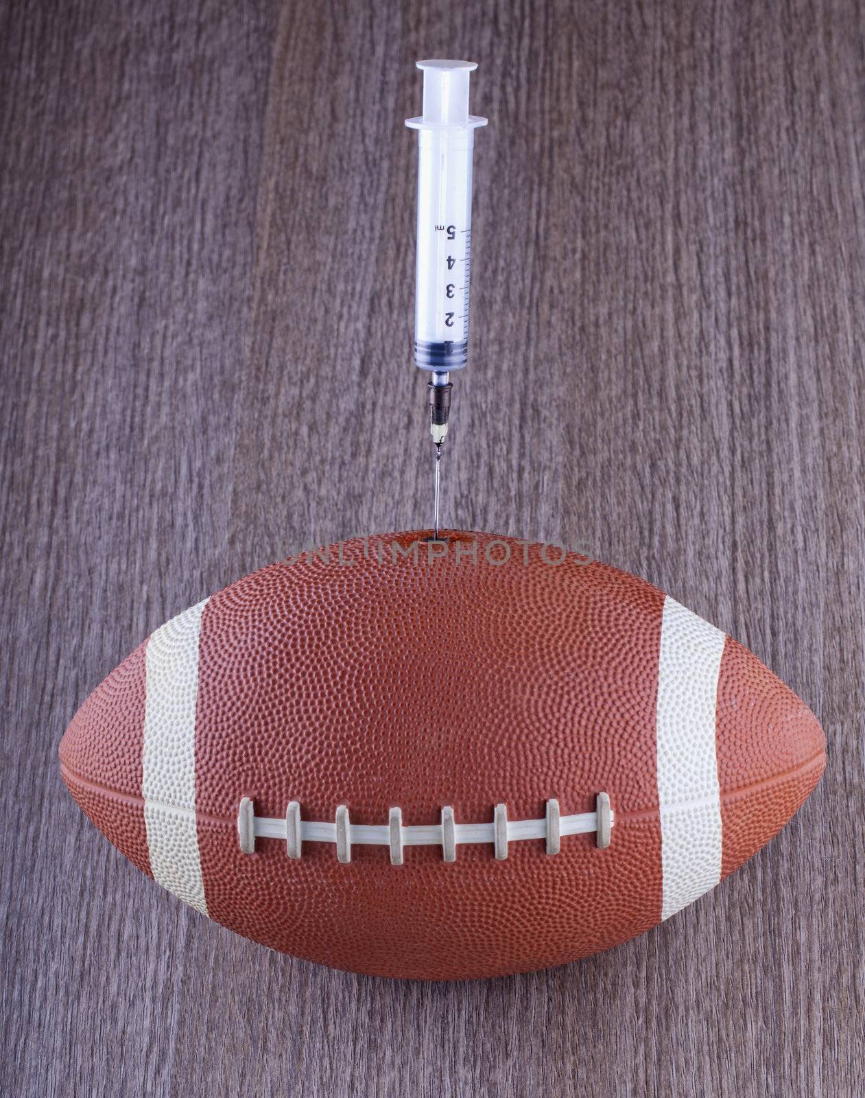 A football with a syringe injecting over wooden background