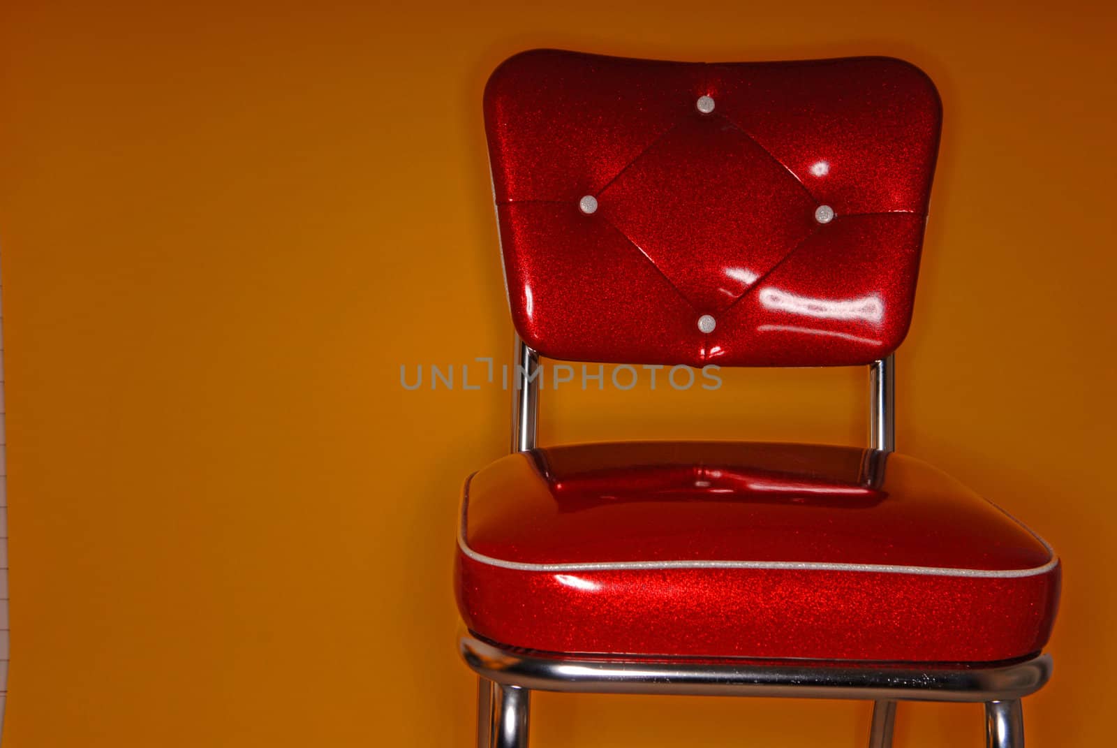 A red vinyl vintage chair on an orange background