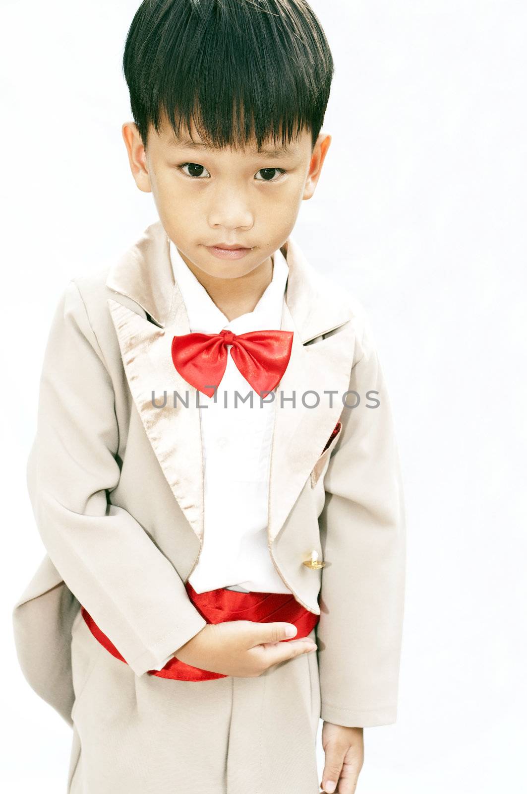 Little boy with brown tuxedo and red bow tie on white background