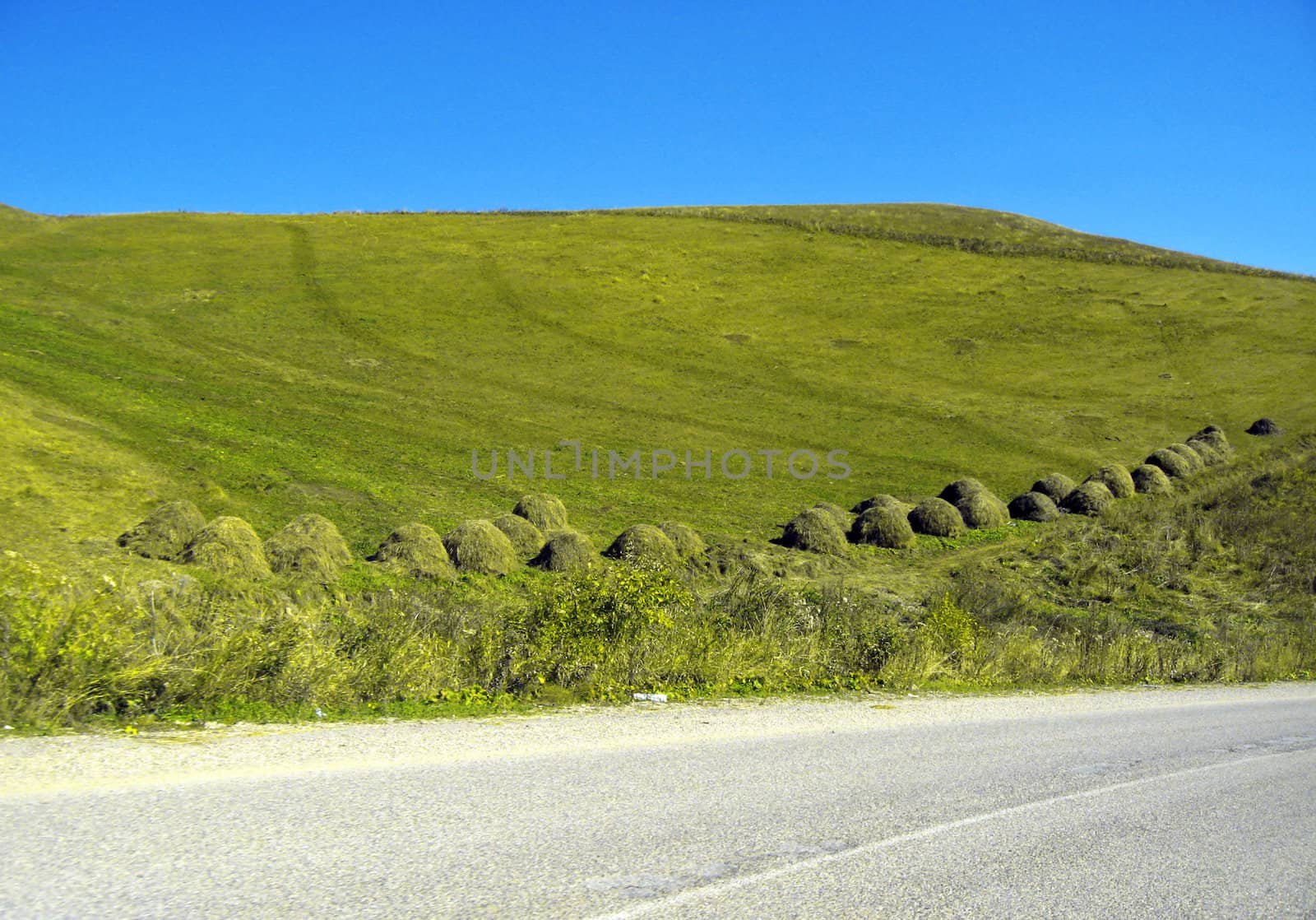 Caucasus autumn landscape. Stacks of dry grass along the road