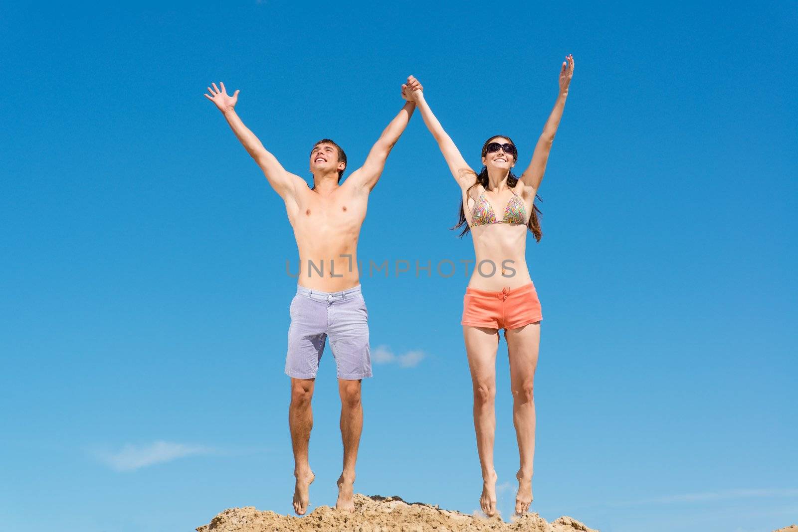 couple jumping together holding hands on a background of blue sky