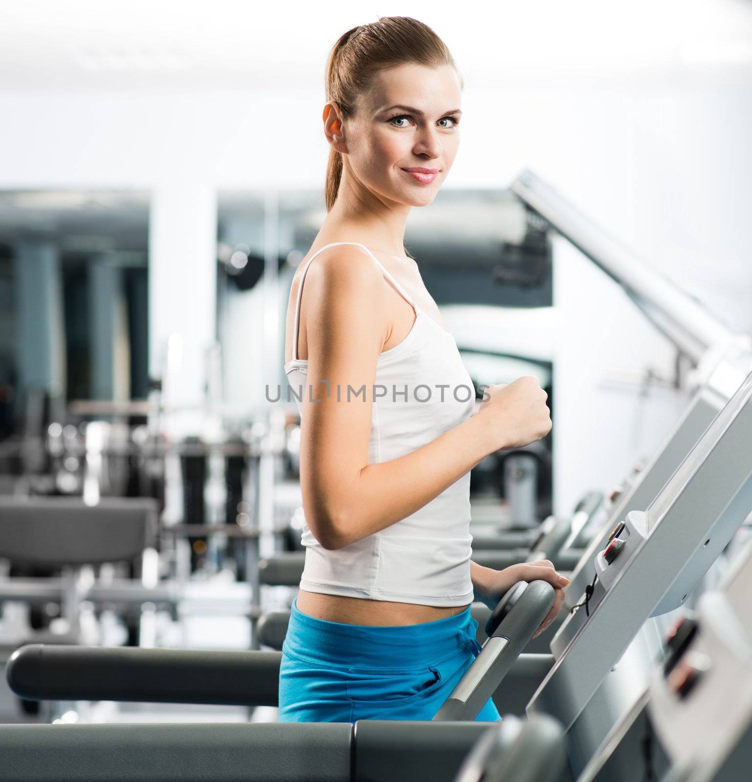 attractive young woman runs on a treadmill by adam121