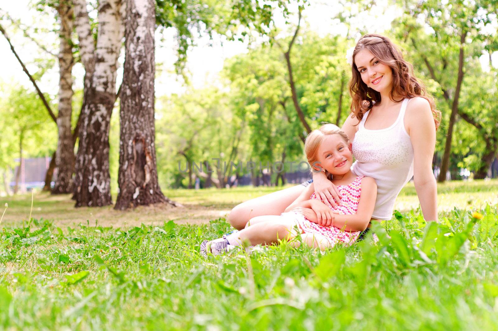 mother and daughter sitting together on the grass, and spend time with family