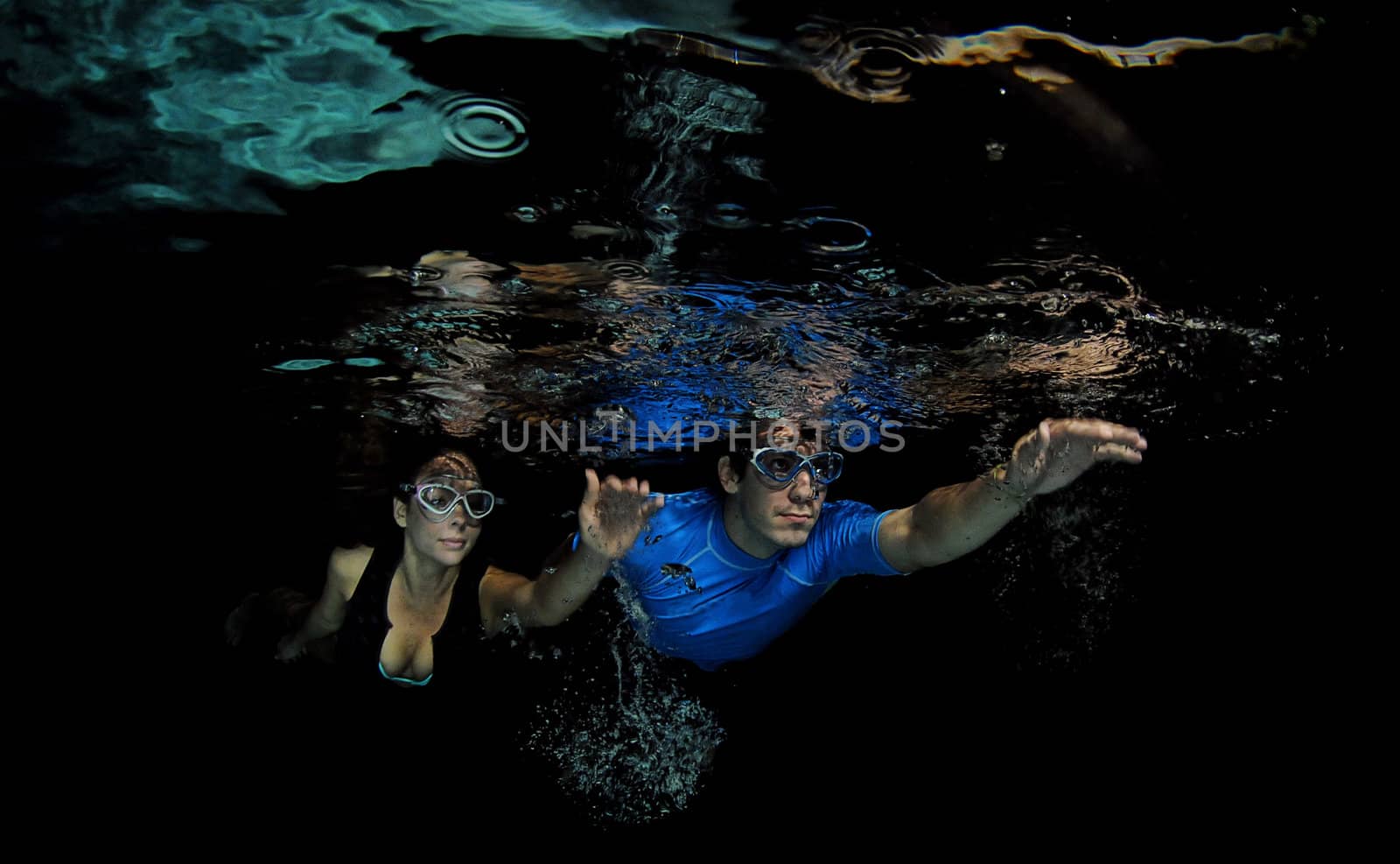 Attractive man and woman swimming underwater with goggles