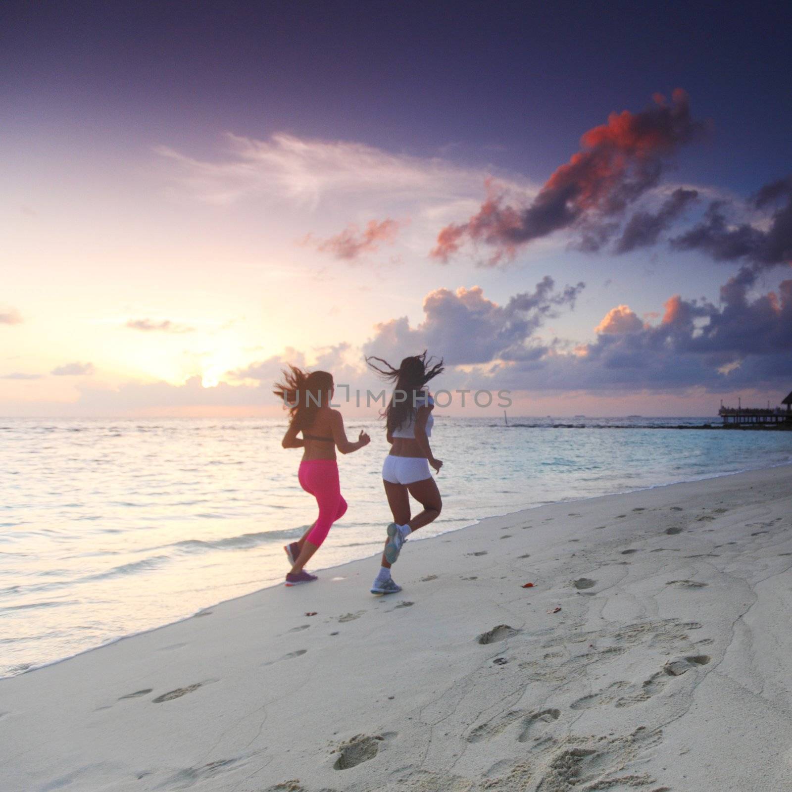 Fitness sport women running on beach at sunset