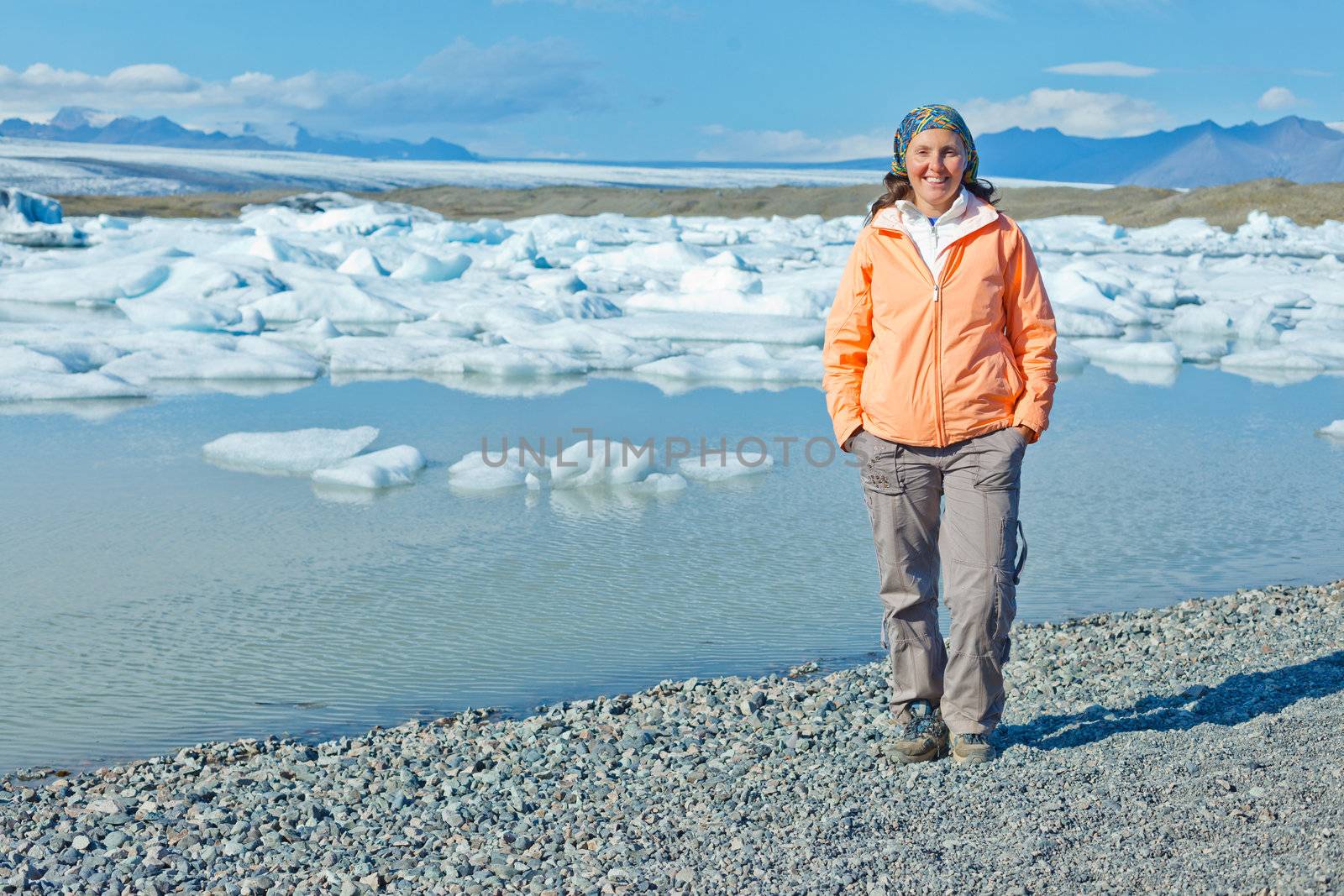 Young woman walking near Jokulsarlon a lake in Iceland where icebergs collapsing from Vatnajokull glacier are floating around.