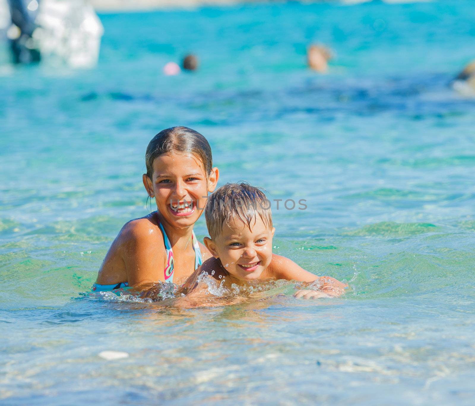 Happy kids. Sister and brother playing and swimming in the transparent sea