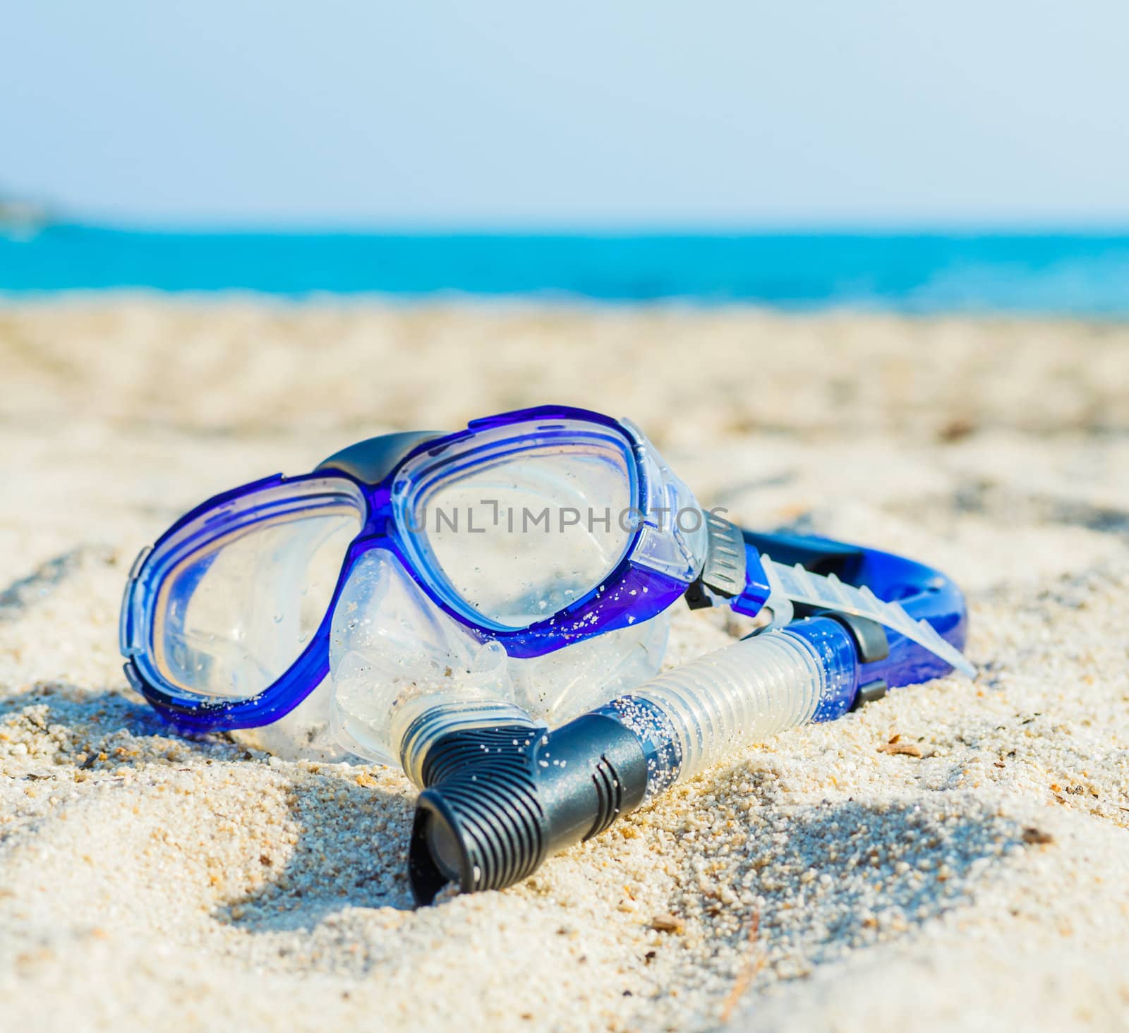 Snorkeling set. Blue diving goggles on sea beach