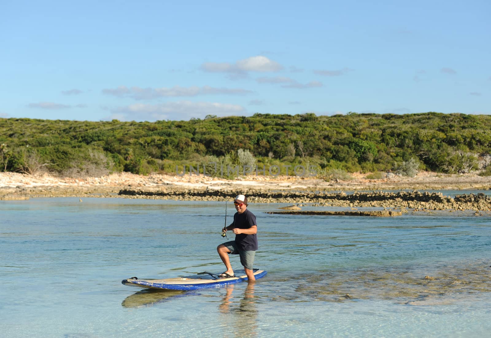 Man stepping off paddleboard while fishing in scenic tropical destination