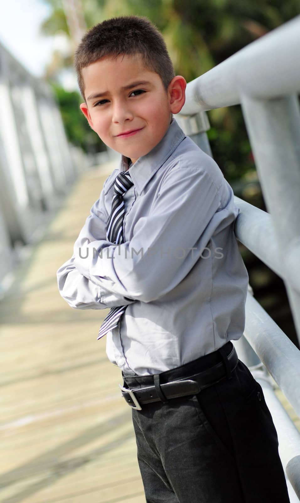 Serious young boy outdoors in suit with arms crossed