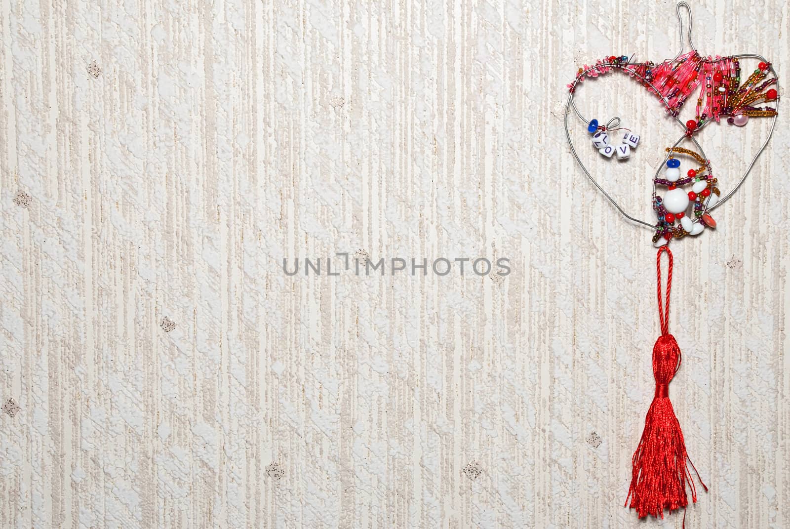 Decorative heart from colorful beads on a textured background.