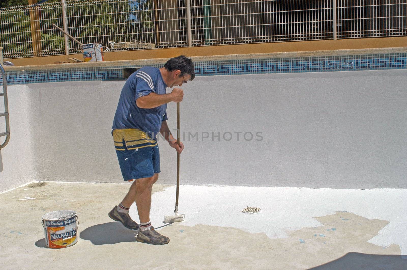 painter painting the bottom of a swimming pool                                