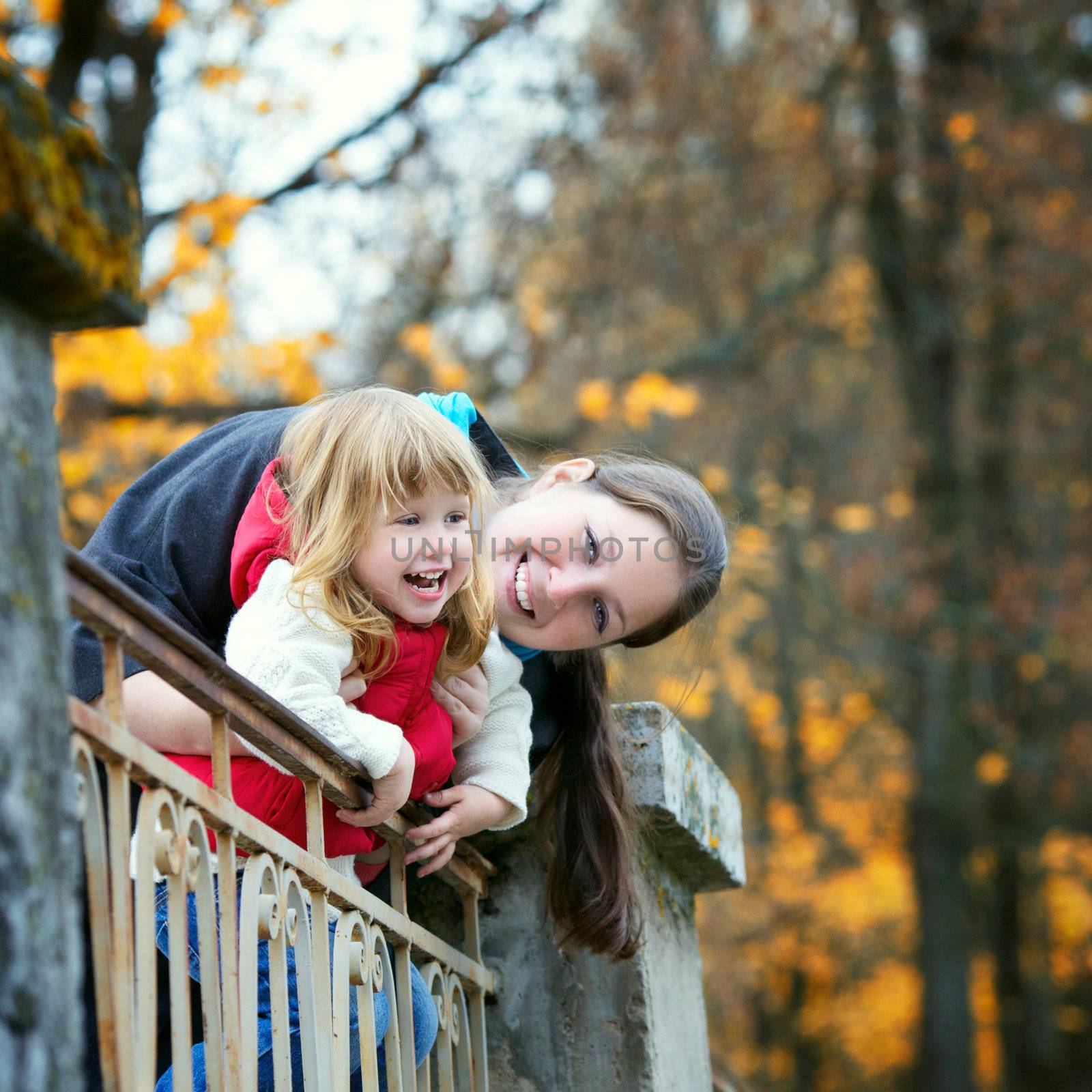 beautiful little girl and mother on a bridge in autumn park