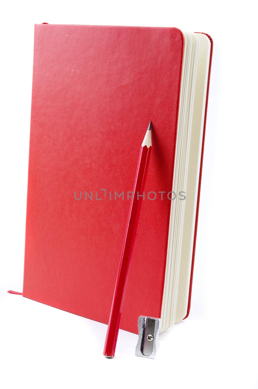 closed red notebook and pencil with sharpener by Triphka