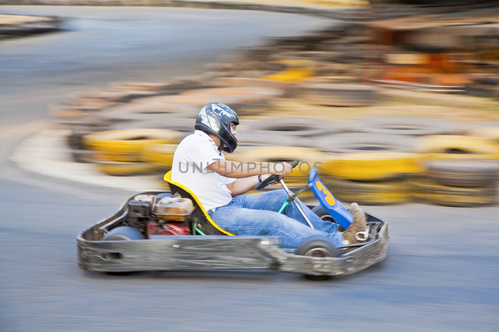 Horizontal take of an Asian driver and go kart as they zoom past on a public race track in Goa India