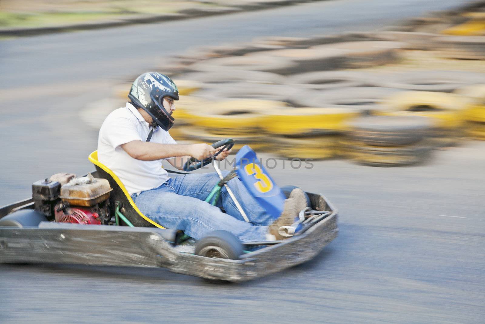 Horizontal generic grab at a public go kart track in Goa during a race as driver number 3 zooms past