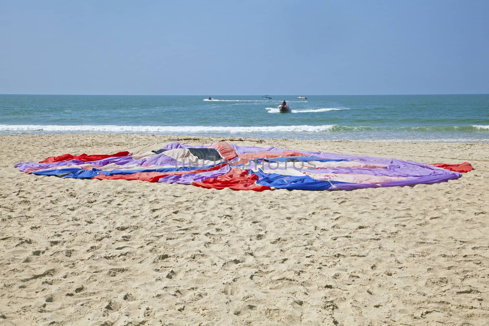 Generic beach landscape of seaside activity and sports. Team of assistants getting a parachute ready for the client high flyer customer