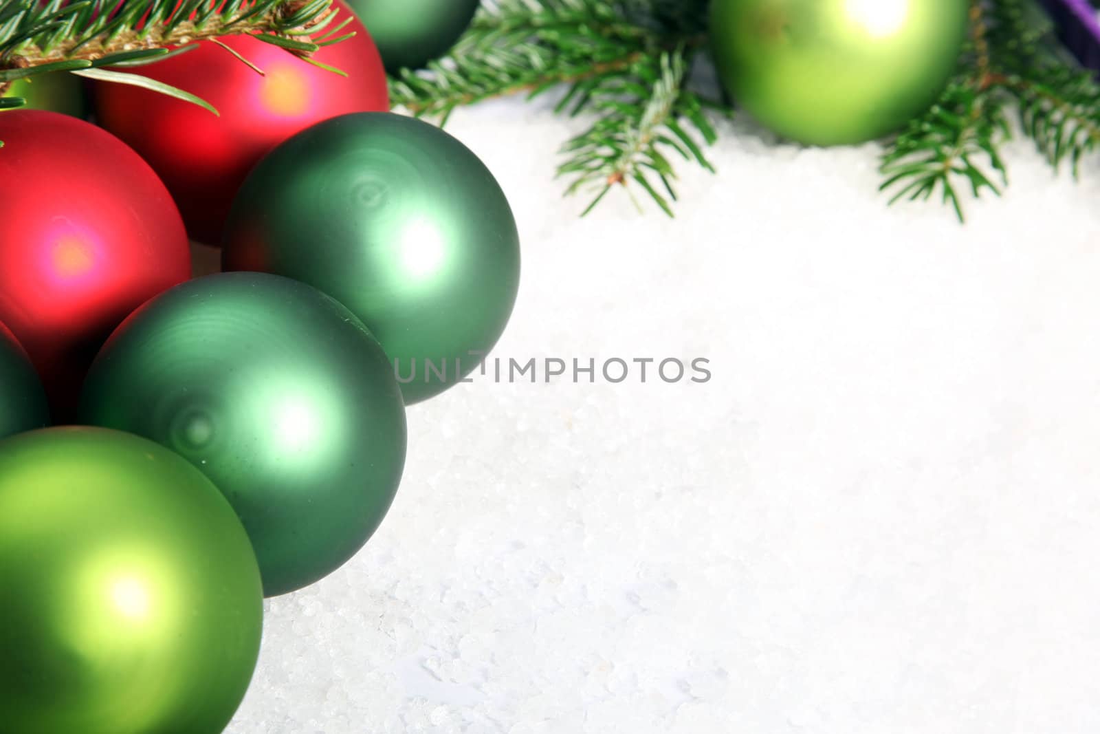 Several red and green Christmas baubles on white snow