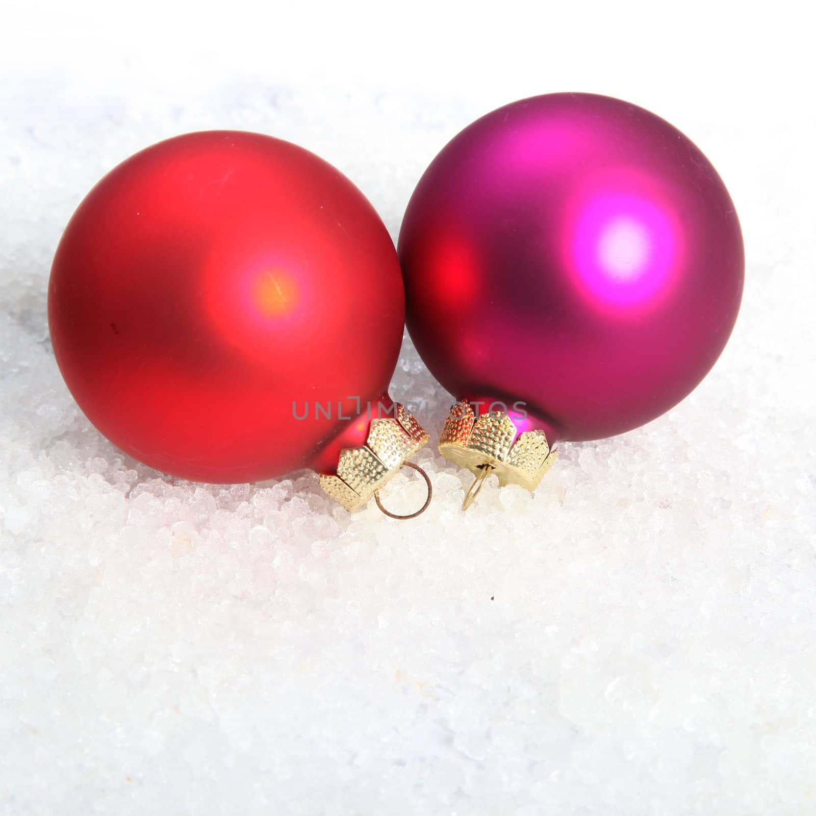 Christmas shiny red and violet globes in snow, close up