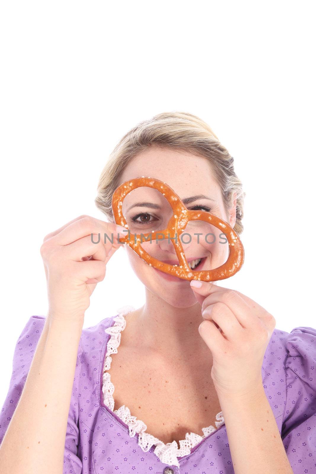 Portrait of a funny blond girl wearing a dirndl and holding a bretzel to her face