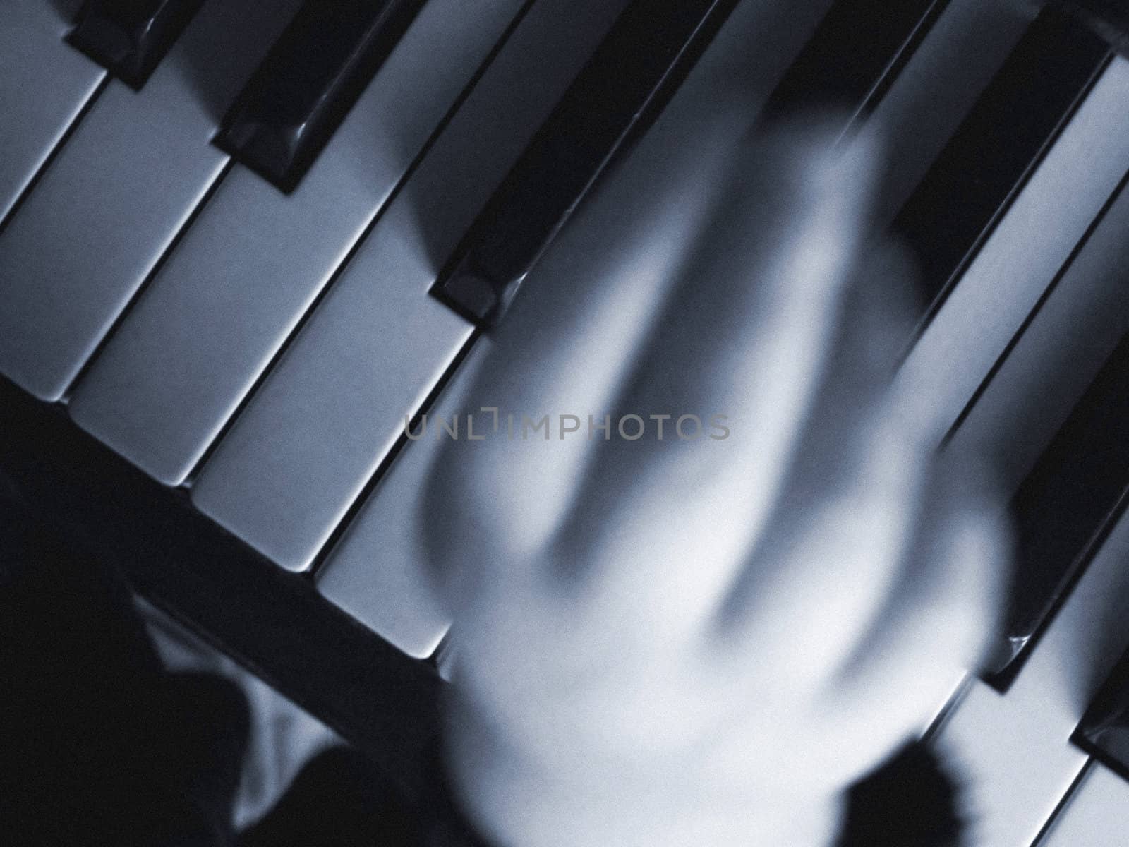 Two years old boy playing the piano indoor at available light. Filmgrain added. Motion blur.