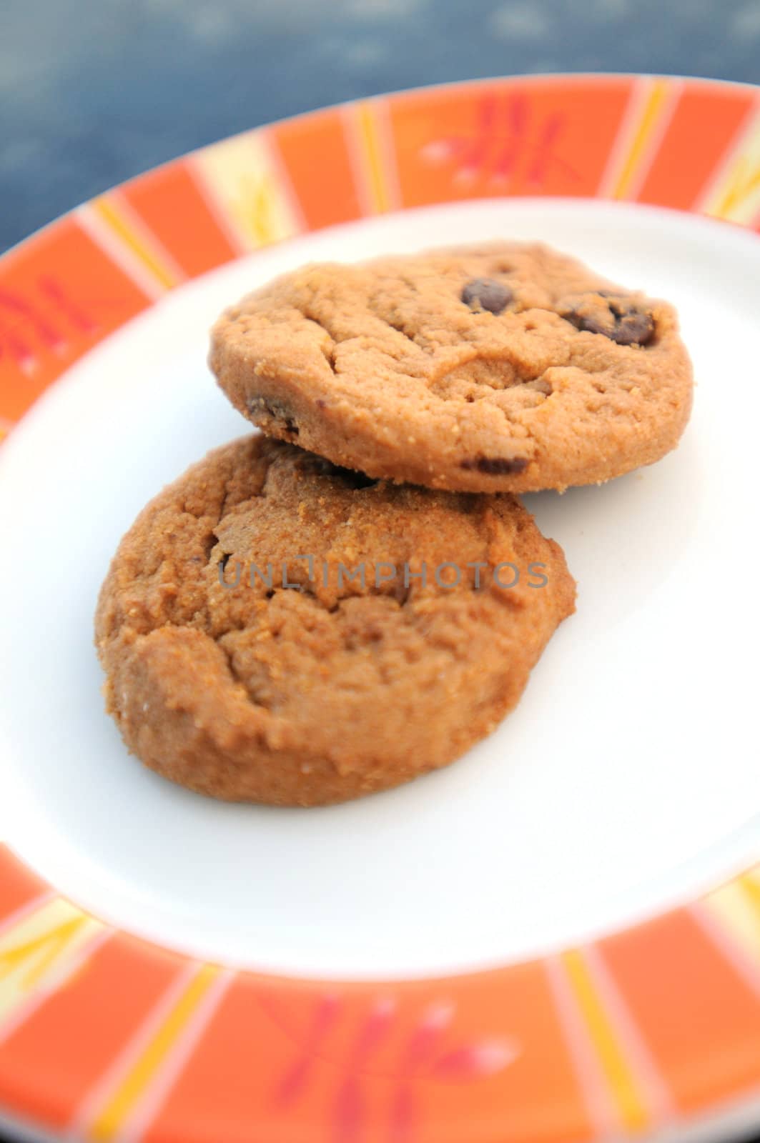 a chocolate chip and a peanut butter cookie on an orange and white plate