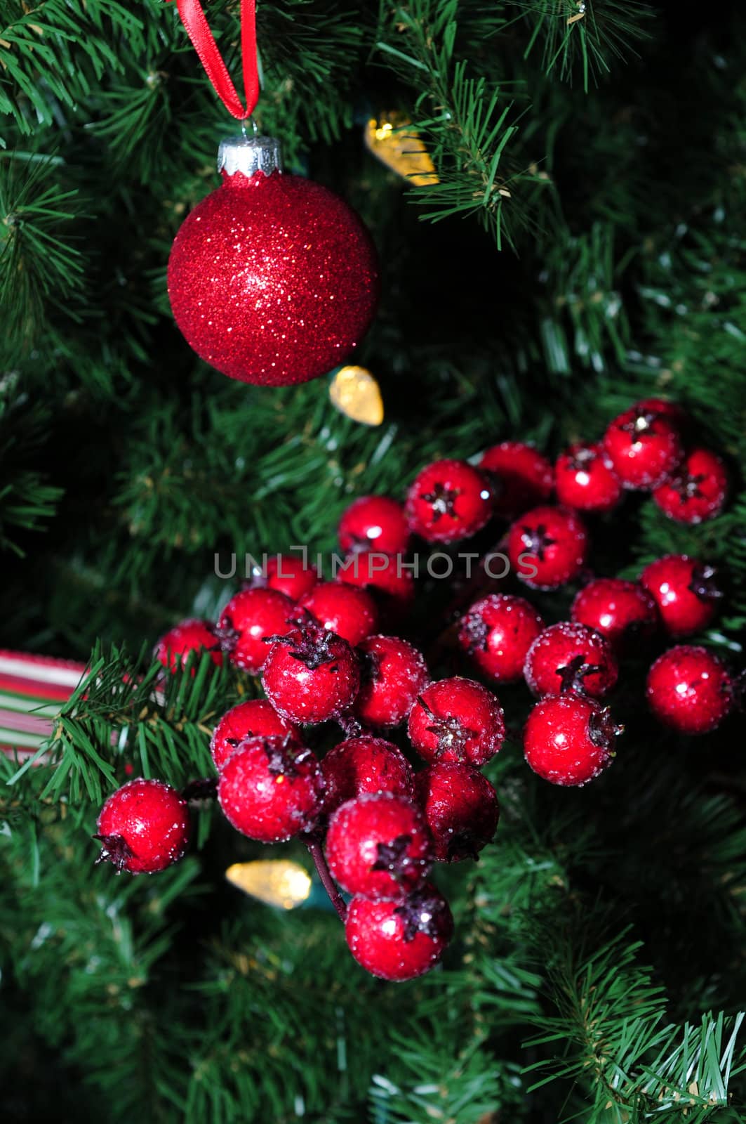 red holiday berries and ornaments on a lit christmas tree