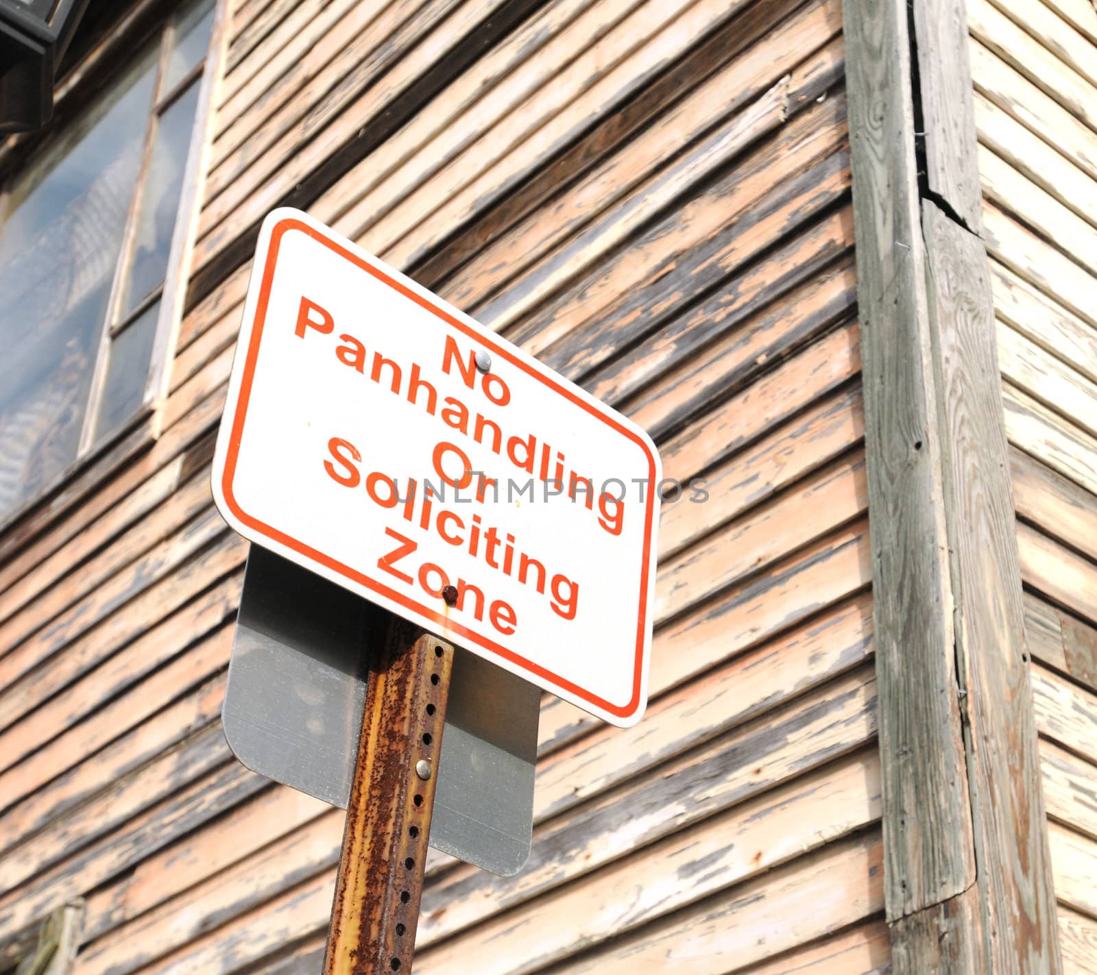 no panhandling or soliciting zone sign near wooden building