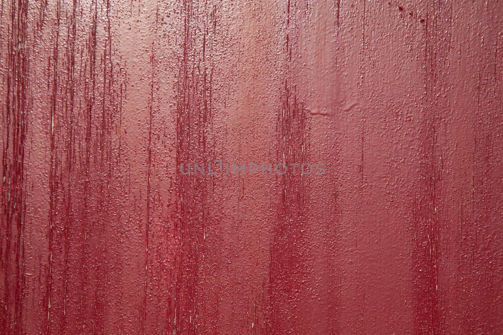 A background of red cracked and flaky  paint with vertical tones.