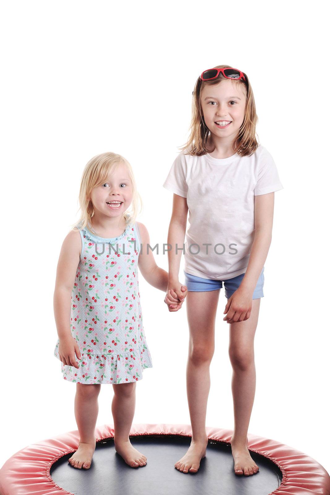 cute little girls holding hands on a trampoline, against white background